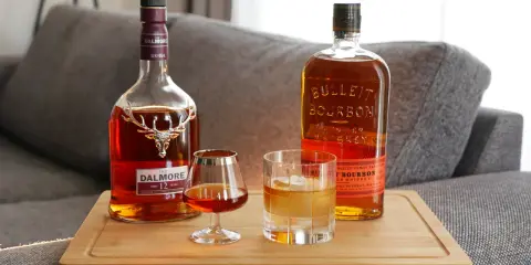 Zwei Flaschen Whiskey, Dalmore und Bulleit Bourbon, und zwei Gläser zeigen die whiskey unterschiede.