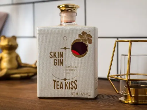 Flasche "Skin Gin Tea Kiss" neben einem goldenen Frosch und Kerzenhalter. Die Frage, wie viele Gin-Sorten es gibt, bleibt offen.