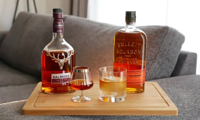 Zwei Flaschen Whiskey, Dalmore und Bulleit Bourbon, und zwei Gläser zeigen die whiskey unterschiede.