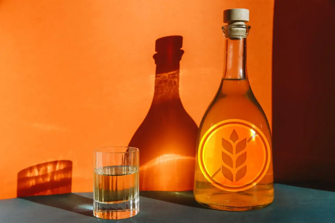 Flasche und Glas mit bernsteinfarbenem Getr&auml;nk, das Symbol f&uuml;r whiskey glutenfrei auf der Flasche.